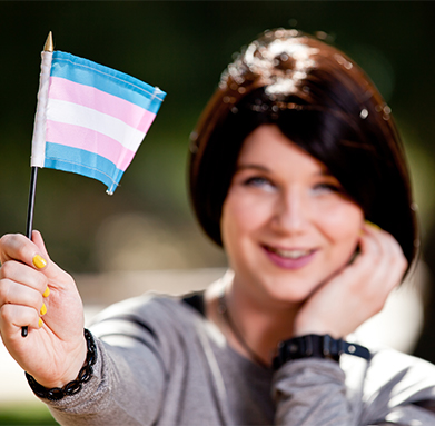 young adult holding the trans flag