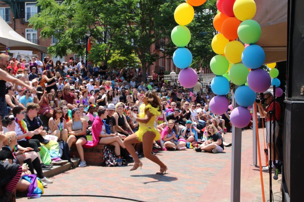 drag queen dressed in yellow running through audience at pride parade