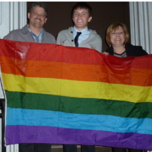 three people holding rainbow flag