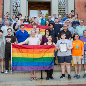 Frederick center members standing on stairs holding pride flags