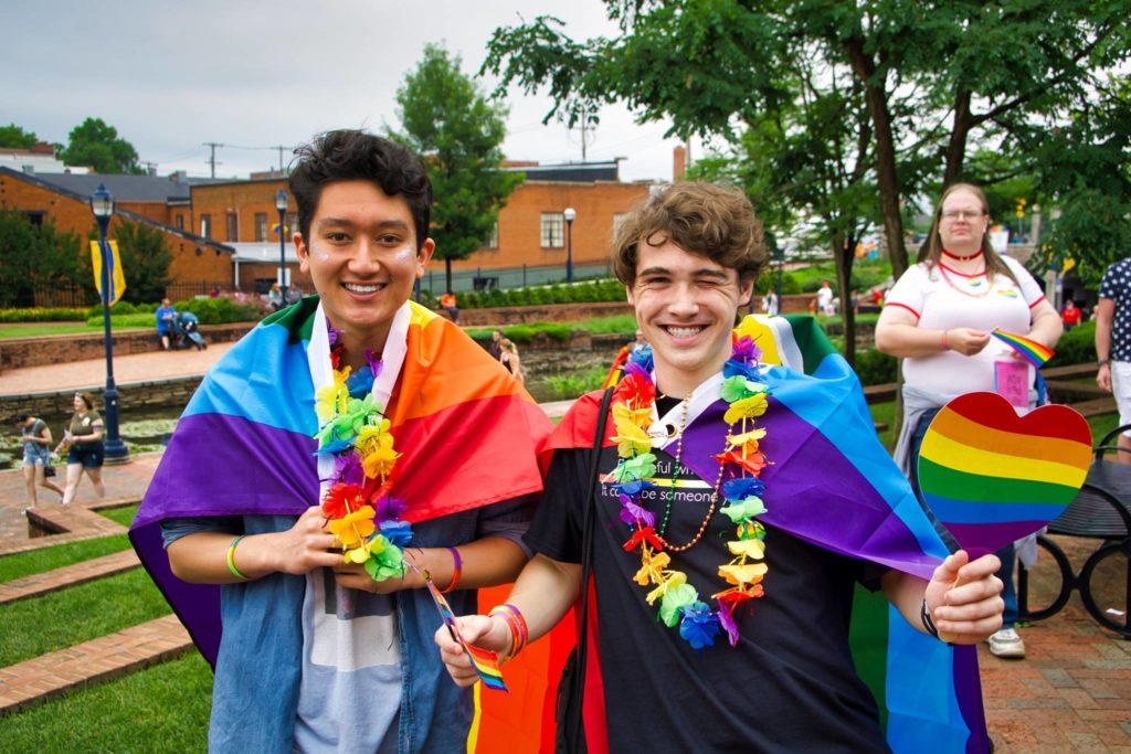two friends wearing rainbow pride flags and rainbow leis