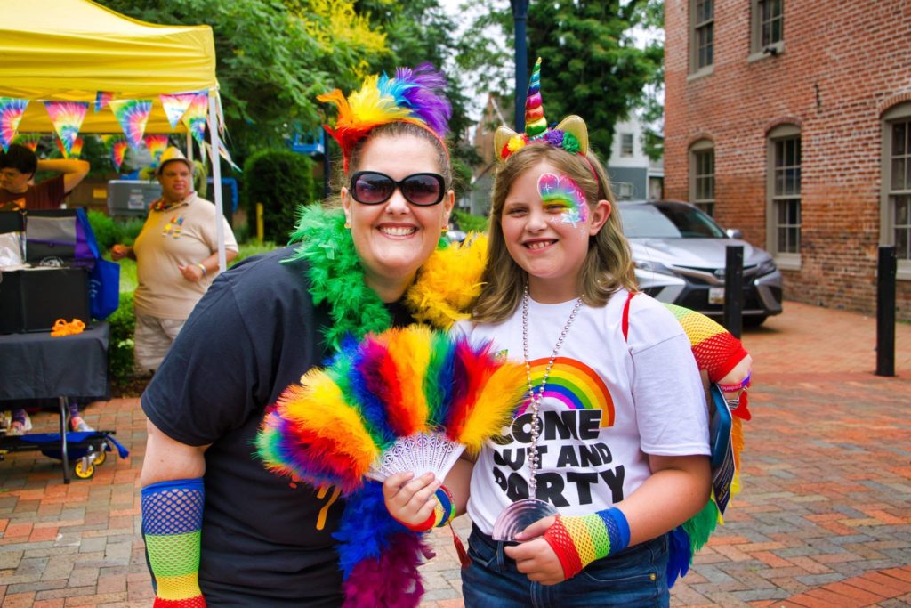 mother and daughter dressed in rainbow colors smiling at camera