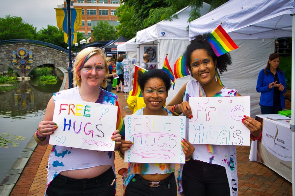 group of friends holding free hugs signs at frederick pride
