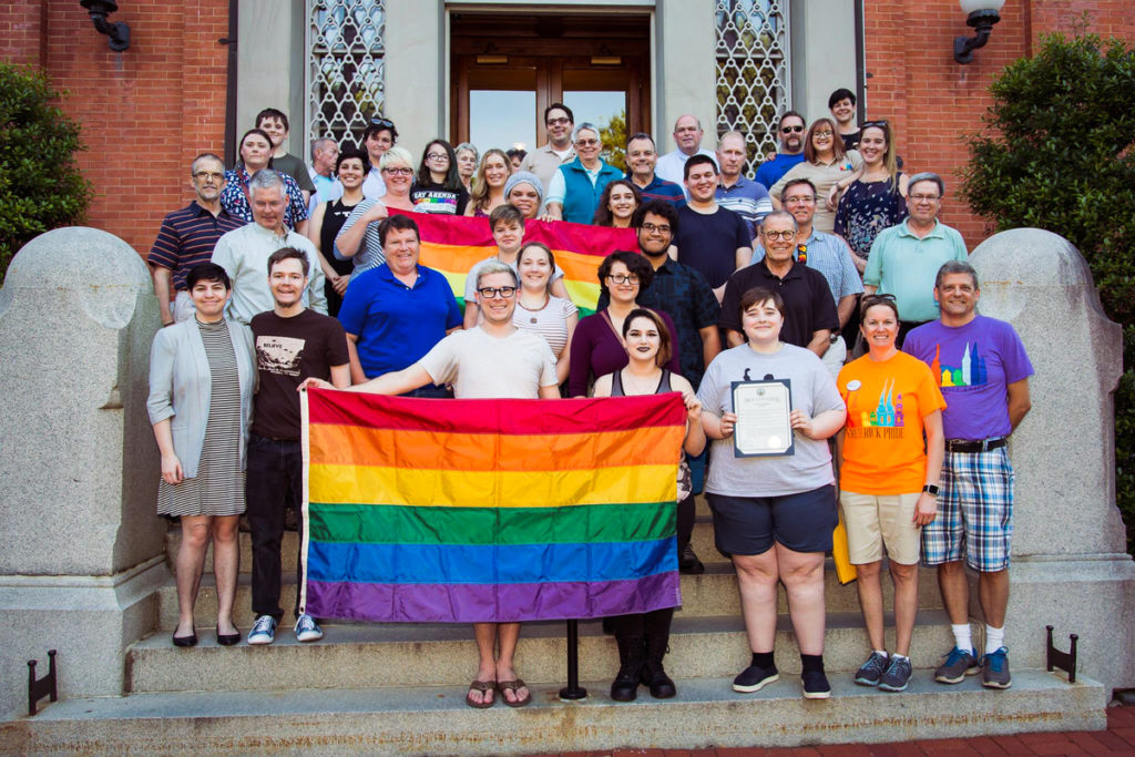 group of volunteers smiling and holding rainbow flags