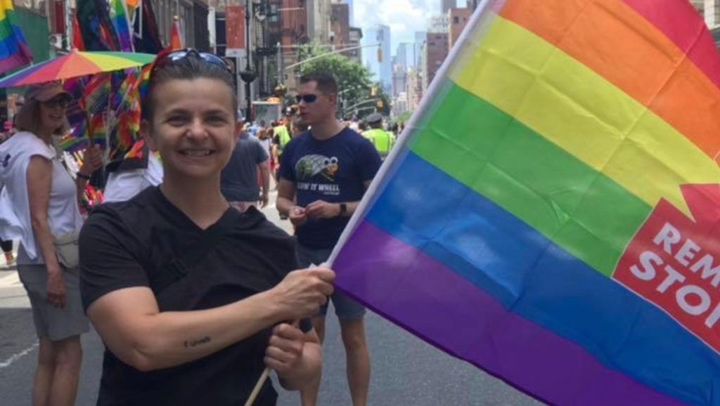 person at pride holding rainbow flag and smiling